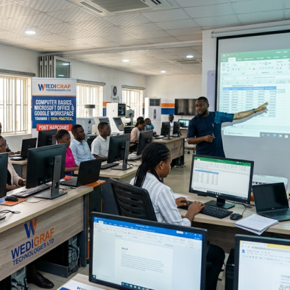 Students and a male instructor inside a modern ICT training center, 100% focused on hands-on practical learning on desktop computers, building an automated Excel financial model at Wedigraf Technologies Ltd in Port Harcourt, Rivers State.
